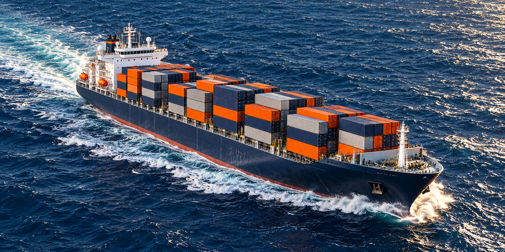 Navy cargo ship sailing through ocean waves with a foaming bow wave and long wake